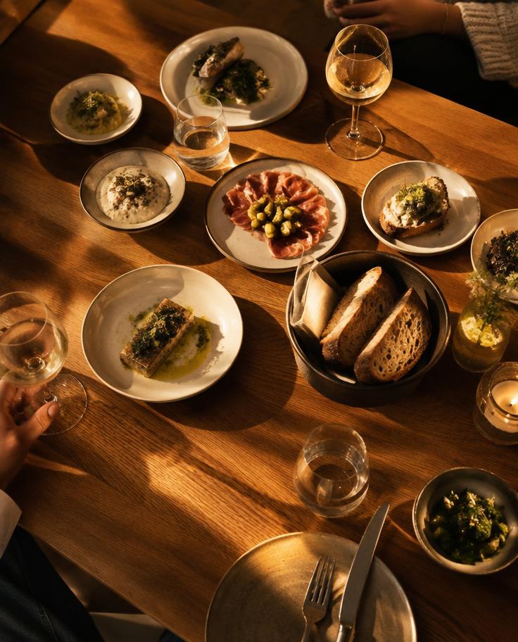 Bord med små tallrikar, bröd och vin i kvällsljus